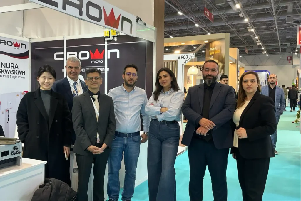 Seven professional team members posing at a Crown Micro trade exhibition booth for renewable energy solutions.