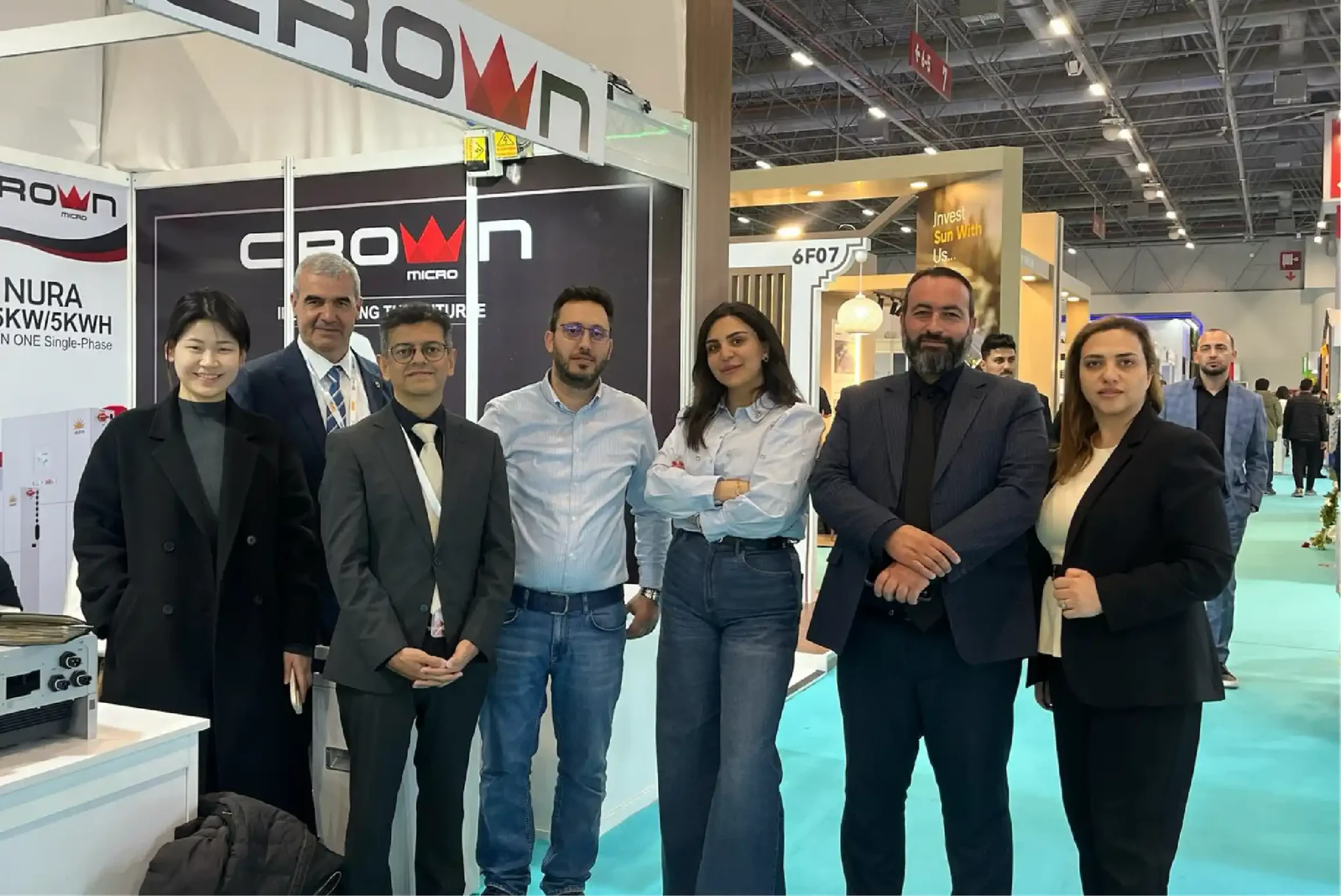 Seven professional team members posing at a Crown Micro trade exhibition booth for renewable energy solutions.