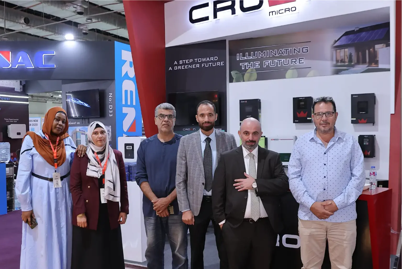 Six team members posing at a Crown Micro solar exhibition stand featuring smart grid inverters.