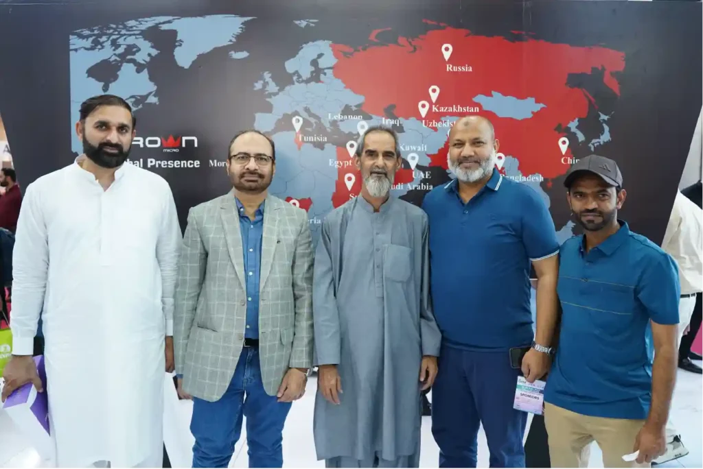 Five men standing together in front of a Crown Micro global presence world map banner at a business event.